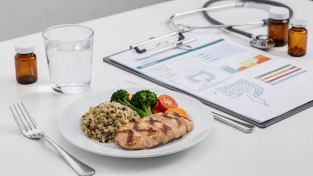Glutenfreie Mahlzeit und medizinische Unterlagen zu Zöliakie-Begleiterkrankungen auf einem Tisch